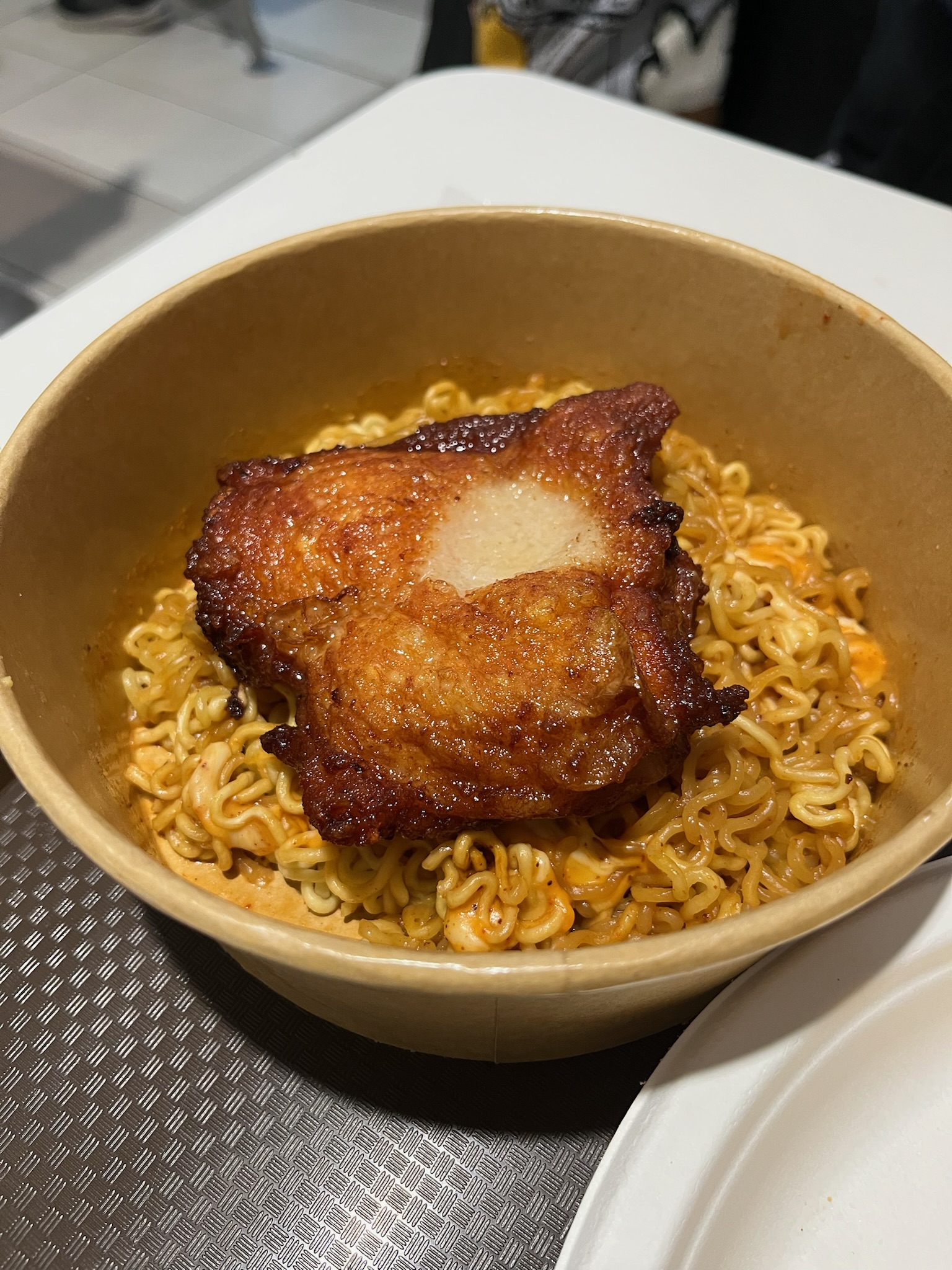 Close-up of the crispy chicken cutlet resting on Korean instant noodles in soy milk broth