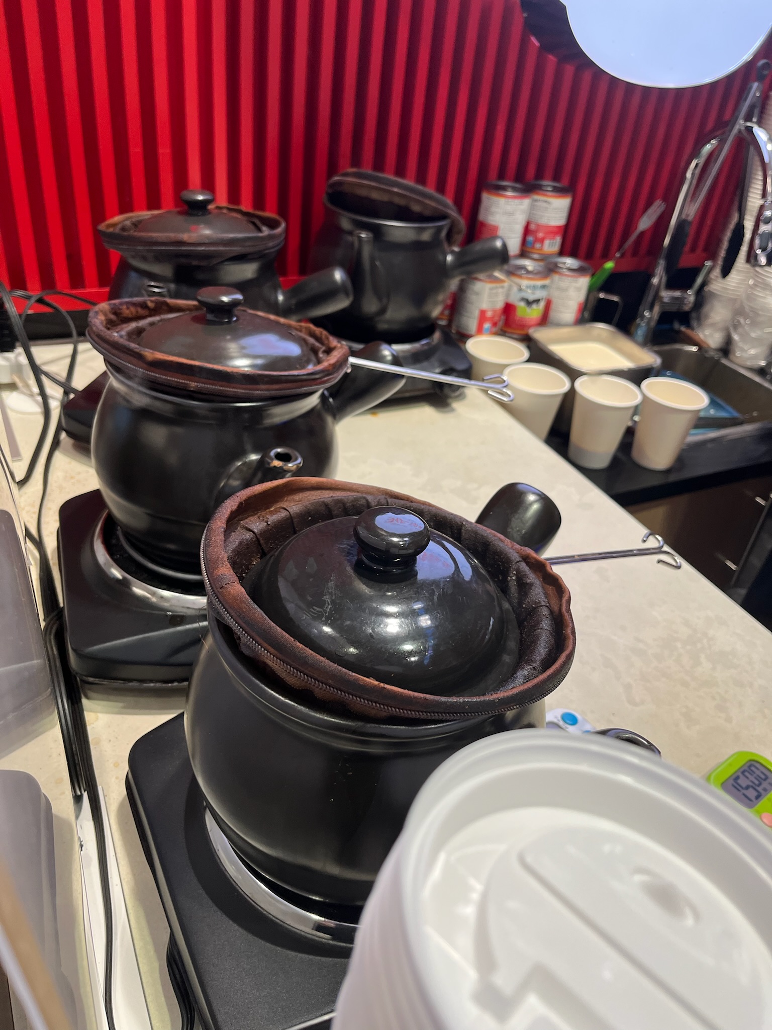 Three black clay pots on burners — the traditional Hong Kong milk tea brewing setup