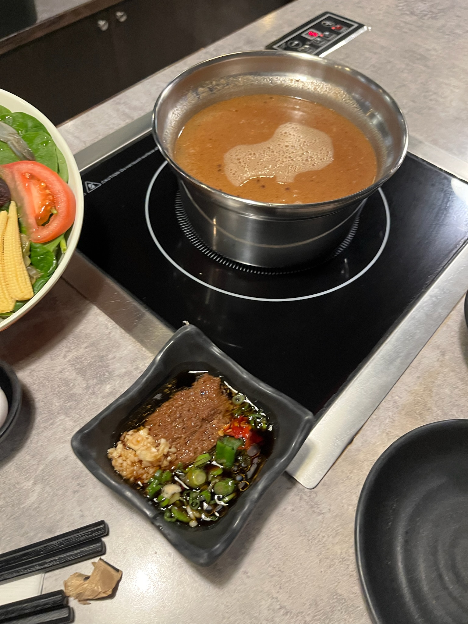Satay broth at a rolling boil on the induction cooktop